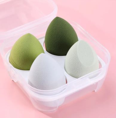 Le set Éponge de maquillage (4 pièces) de My Store, en vert, olive, gris et blanc, est présenté dans un boîtier transparent sur fond rose. Parfait pour une application impeccable à tout moment.