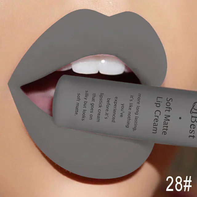 A close-up of lips in gray Matte Non-Stick Liquid Lip Gloss - Long-Lasting Finish by Léa Beauty & Cosmetics, holding the tube between the teeth with visible text and the number 28# shown in the bottom right corner.