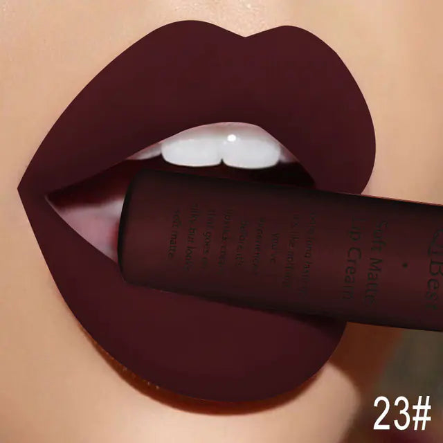 Close-up of lips wearing Léa Beauty & Cosmetics Matte Non-Stick Liquid Lip Gloss - Long-Lasting Finish in dark burgundy, holding the matching tube between their teeth. 23# is shown in white at the bottom right corner.