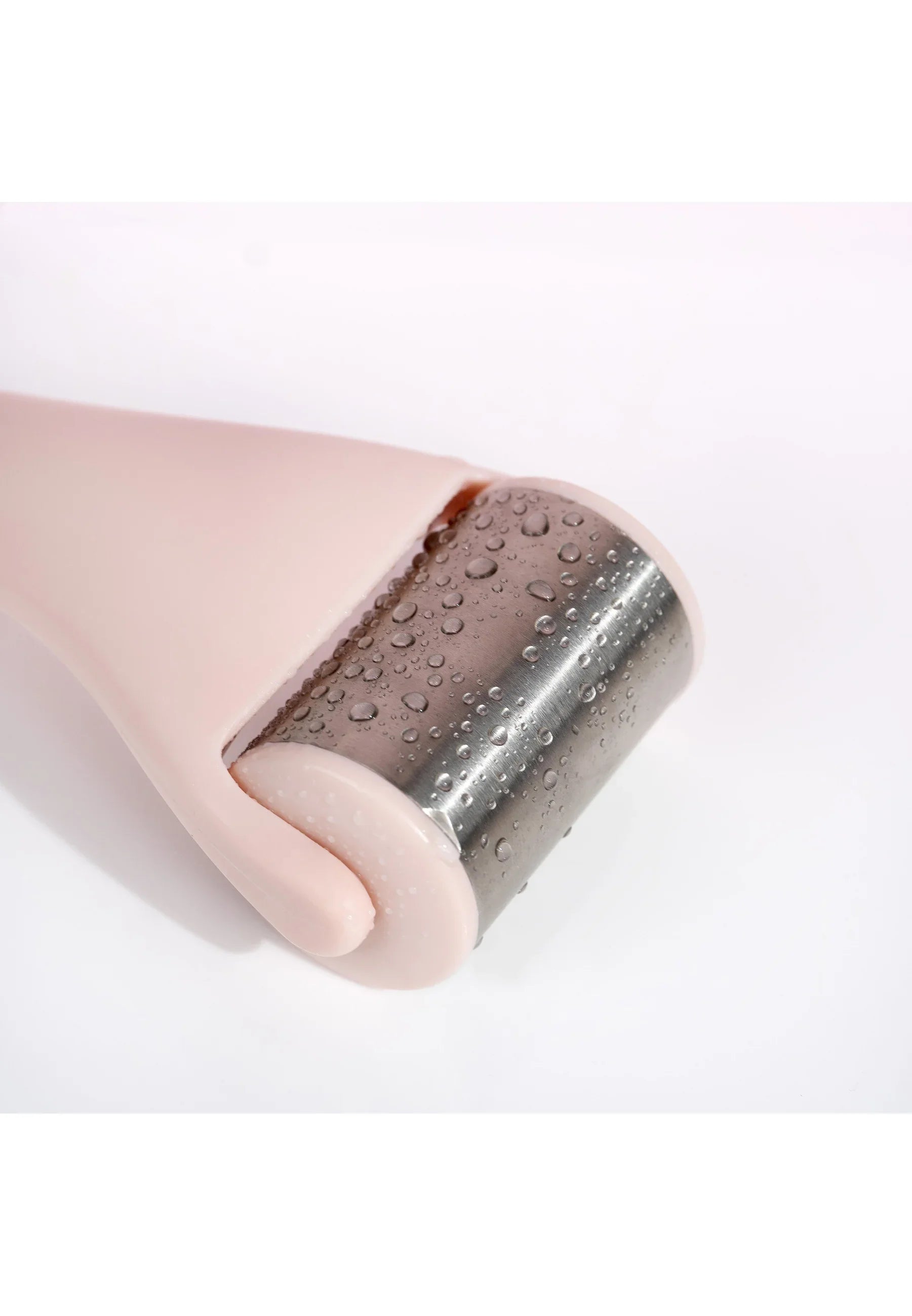 A close-up of My Stores Roulette de glace with a pink handle and water droplets on its metal surface, placed on a white background, delivering instant relief and a sensation of freshness.