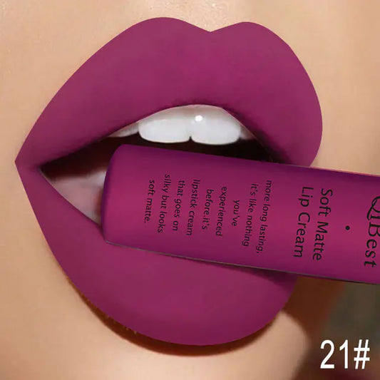 A close-up of lips in matte purple, holding a Léa Beauty & Cosmetics Matte Non-Stick Liquid Lip Gloss – Long-Lasting Finish tube between the teeth. The number 21# is shown in the bottom right corner.